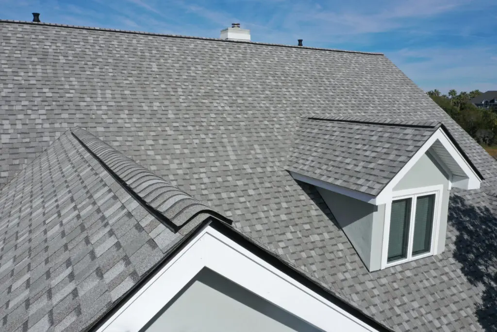 Gray asphalt shingle roof on modern residential home with dormer window and ridge detail