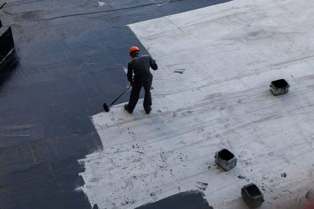 contractor applying coating to commercial flat roof