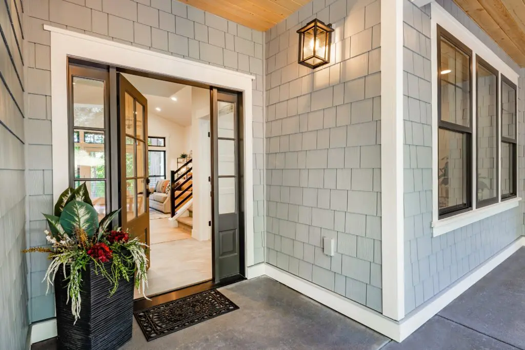 residential front entry with new door, siding, and exterior lighting