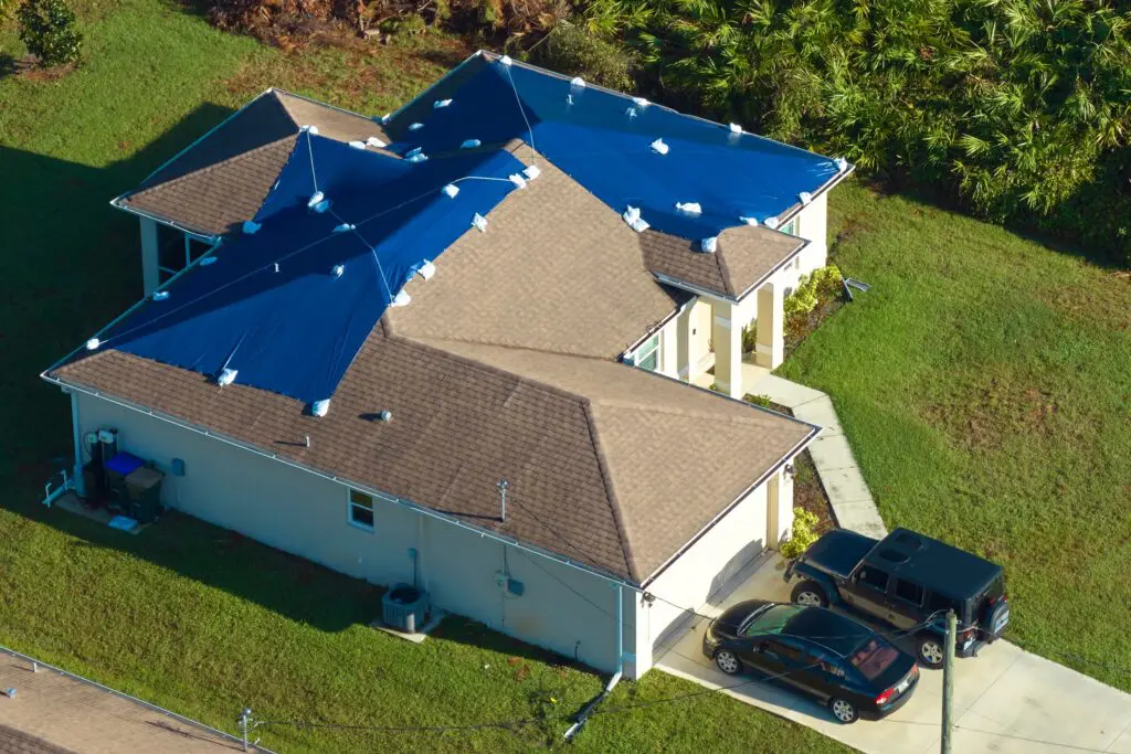 residential roof under replacement with protective tarp sections
